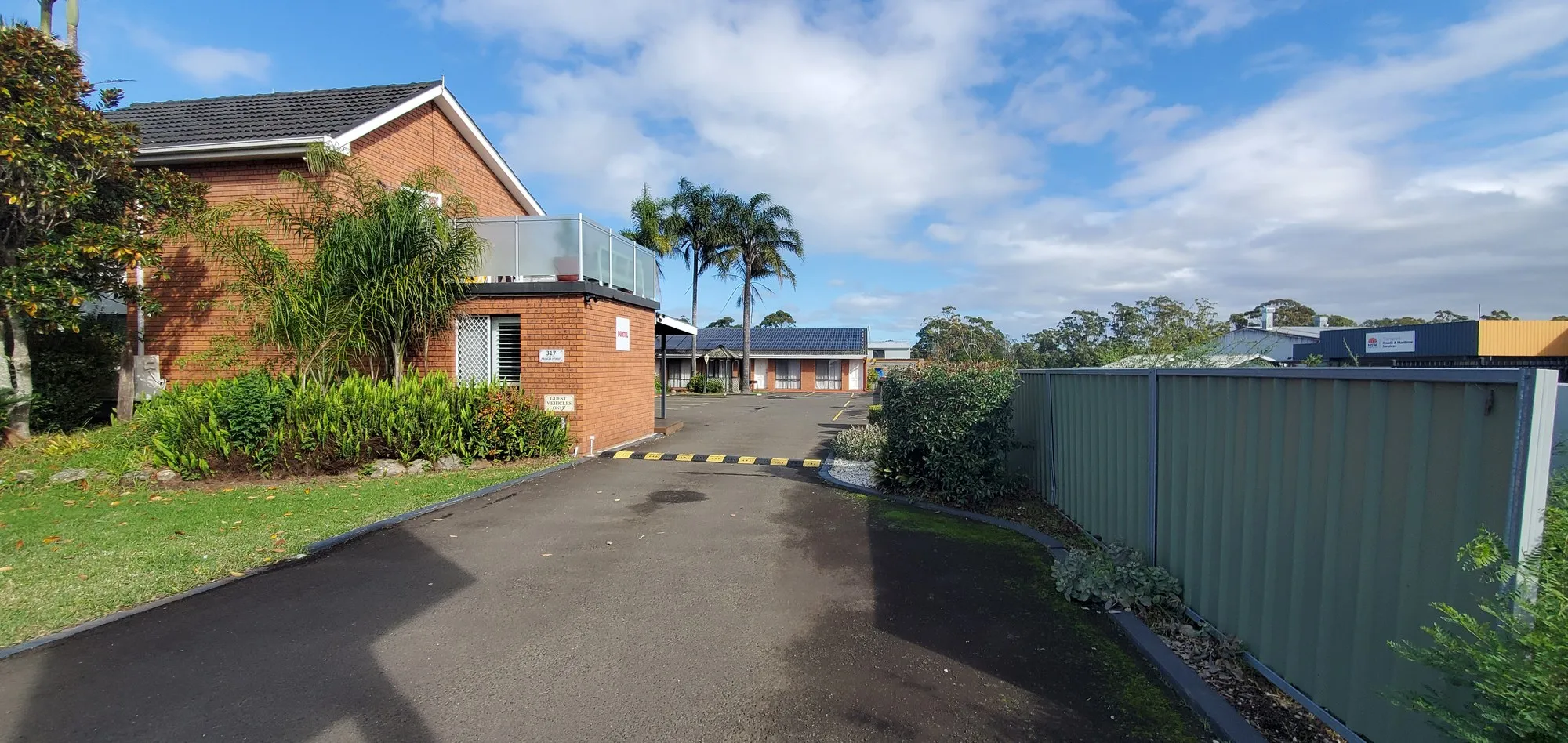 The driveway into Avaleen Lodge Motor Inn: the brick office with its glass balcony, palms and garden
