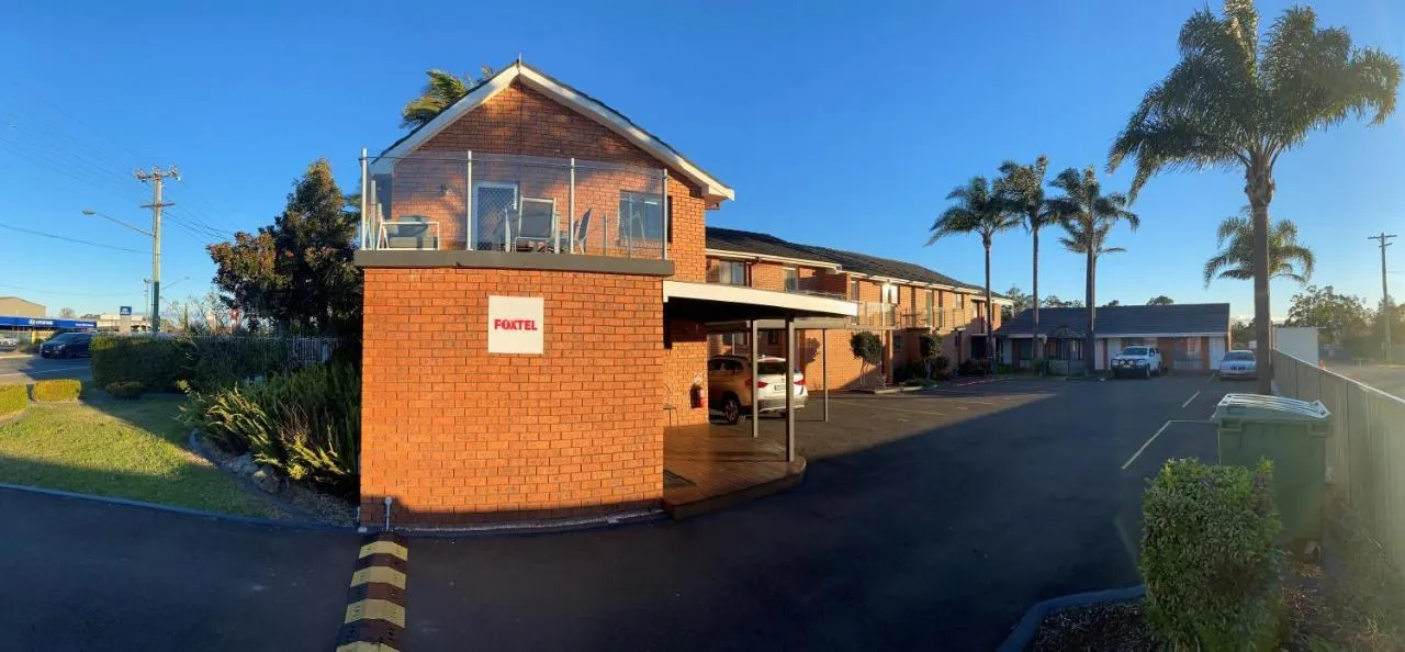 The red brick office and courtyard of Avaleen Lodge Motor Inn under a clear blue sky
